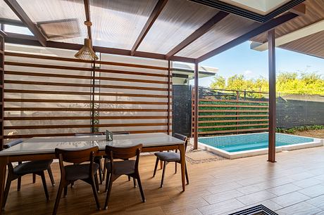 Covered deck with wooden beams, tile floor, and swimming pool visible through slatted screens.