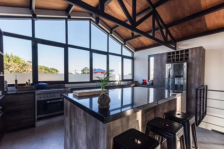 Spacious kitchen with vaulted wooden ceiling, large windows, and modern appliances.
