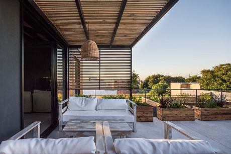 Covered patio with wooden beams, rattan light fixture, and raised garden beds.