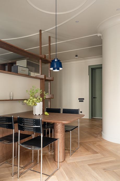 Chic dining area with wooden furniture, modern lighting, and sleek shelving.