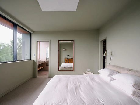 Spacious and minimalist bedroom with large windows, modern furnishings, and neutral color palette.