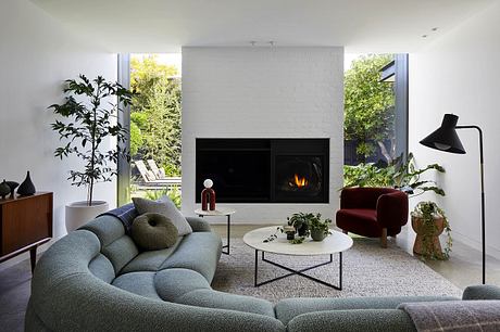Modern, minimalist living room with sleek fireplace, plush seating, and lush greenery.
