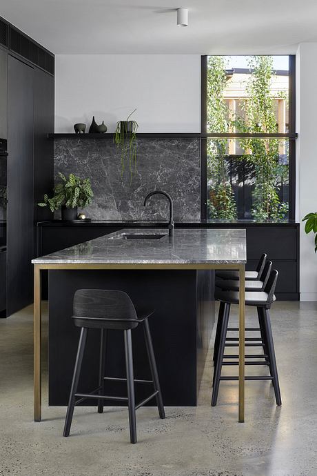 Sleek, modern kitchen with black cabinetry, marble countertops, and a large window overlooking greenery.