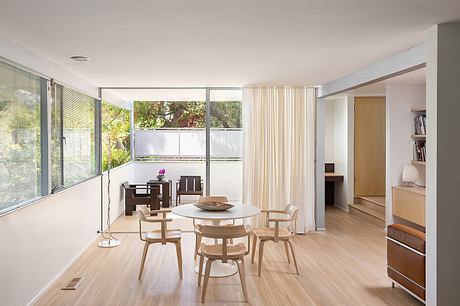 Airy living space with floor-to-ceiling windows, minimalist furniture, and warm wood tones.