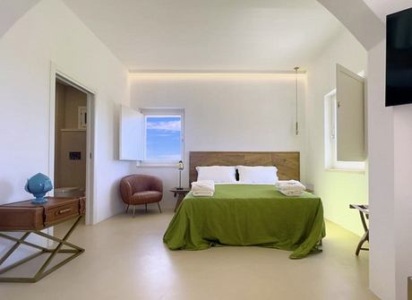 Spacious bedroom with minimalist design, wooden headboard, and green bedding.
