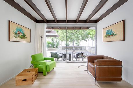 Bright, open living space with wooden beams, large windows, and mix of modern and rustic furniture.
