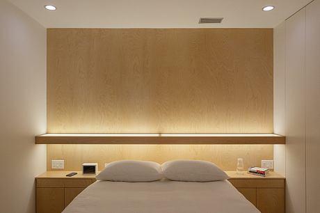 Minimalist bedroom design with wooden paneled walls, floating nightstands, and recessed lighting.