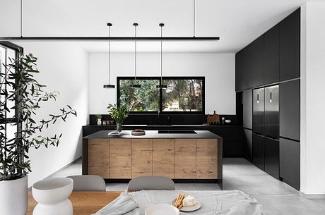 Contemporary kitchen with black and wood cabinetry, large window, and sleek lighting design.