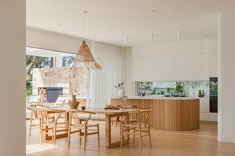 Spacious, modern kitchen and dining area with natural wood accents, stone fireplace.