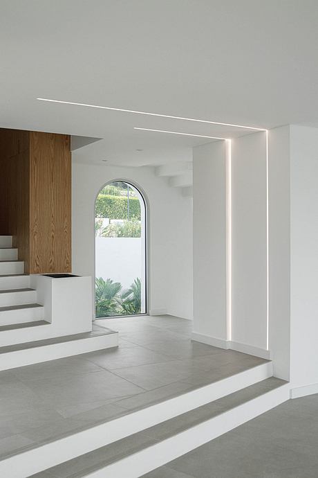 Minimalist interior with an arched window, wood paneling, and stepped concrete flooring.