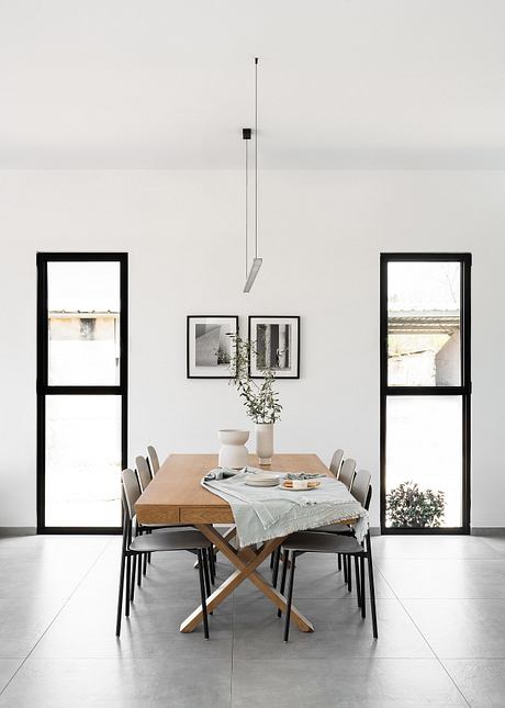 Minimalist dining room with wooden table, black chairs, and framed artwork on the walls.