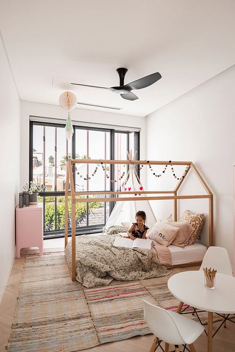 A cozy bedroom with a wooden frame bed, colorful textiles, and a modern ceiling fan.