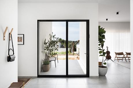 A modern, minimalist interior with large sliding glass doors leading to an outdoor patio.