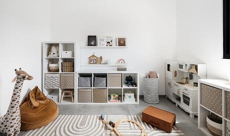 Minimalist children's playroom with built-in storage, cozy rug, and coordinated decor.