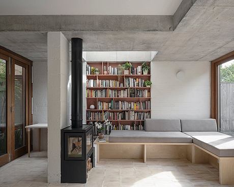 Cozy concrete and wood interior with built-in bookshelf, fireplace, and seating nook.