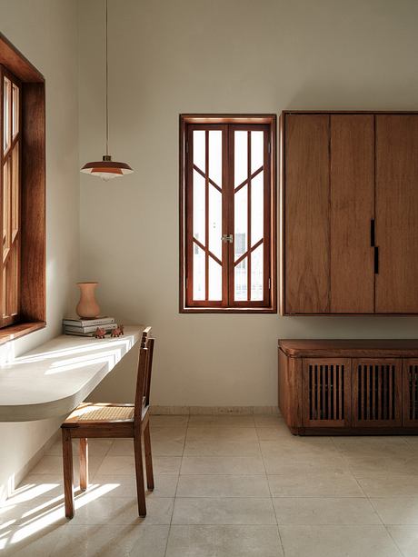 Warm, minimalist interior with wooden furniture, tile flooring, and a large window.