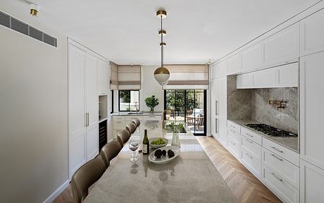 A sleek, modern kitchen featuring neutral tones, minimalist cabinets, and a marble countertop.