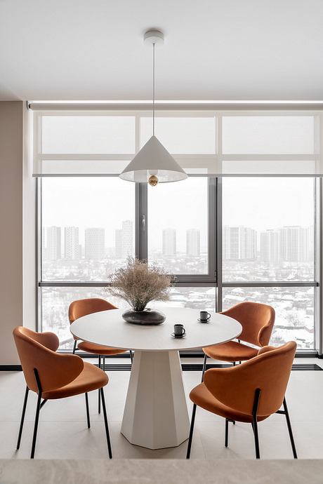 Modern dining area with a round table, pendant light, and leather chairs overlooking a cityscape.