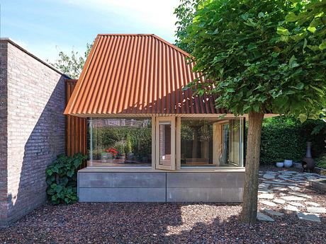 Striking modern architecture with a copper-colored angled roof and glass walls.