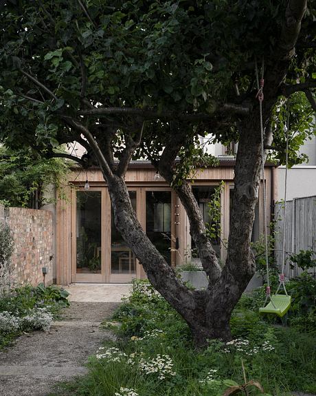 A cozy wooden cottage nestled among lush greenery, with a charming outdoor seating area.