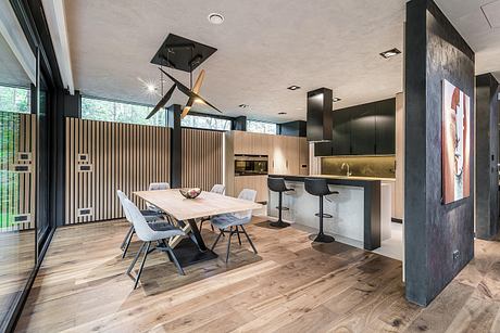Open, modern kitchen and dining area with sleek black and wood design elements.