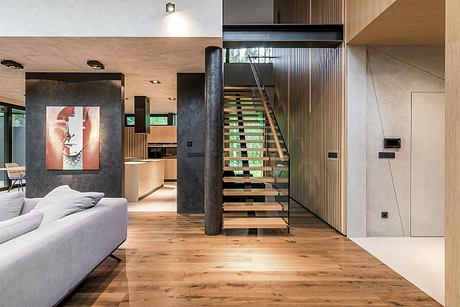 Striking modern interior with open staircase, wooden floors, and abstract artwork.