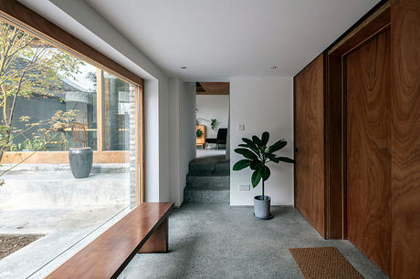 Spacious entryway with stone steps, warm wood tones, and a large potted plant.