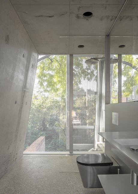 Modern, minimalist interior with large windows overlooking lush greenery outside.
