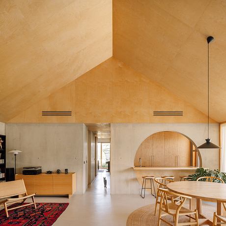 A modern, minimalist interior with natural wood accents, arched doorways, and a cozy seating area.