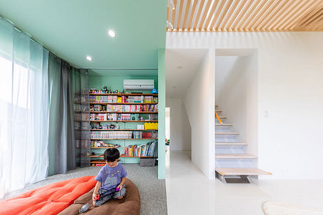 Vibrant mint walls, wooden ceiling, built-in shelving, and cozy seating create a welcoming space.