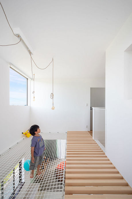 A modern, minimalist interior design with a wooden staircase and suspended light fixtures.