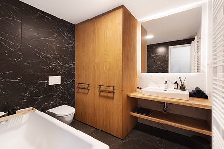 Sleek modern bathroom with black marble walls, wooden cabinetry, and minimalist vanity.