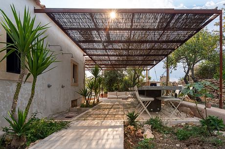 Rustic outdoor patio with thatched roof, stone walkway, and lush greenery.