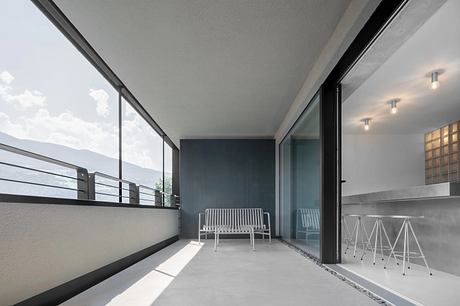 A modern balcony with minimalist furniture, sleek glass doors, and a clean, contemporary design.