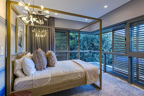 Spacious bedroom with floor-to-ceiling windows, stylish lighting fixture, and plush bedding.