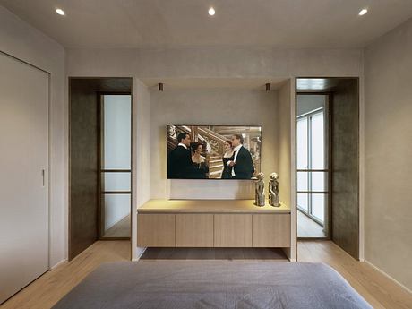 Minimalist interior with wooden furniture, large TV, and decorative figurines on the console.