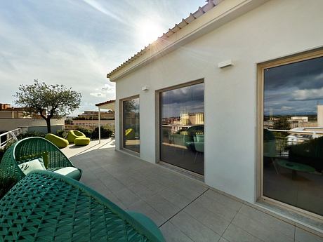 Sleek exterior with glass walls and modern patio furniture overlooking a cityscape.
