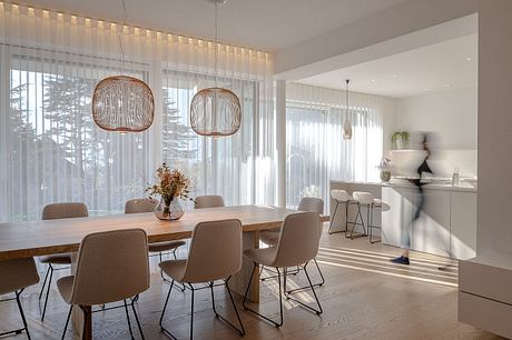 Sleek and modern dining room with large windows, wooden table, and pendant lighting.