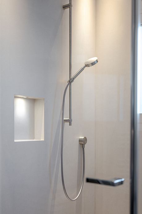 A modern shower with a sleek, minimalist design. The showerhead is adjustable and the fixture has a subtle, unobtrusive presence.