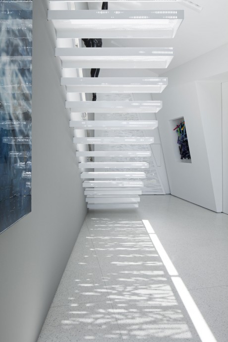 A sleek, minimalist staircase with floating steps and linear lighting in a bright, airy space.
