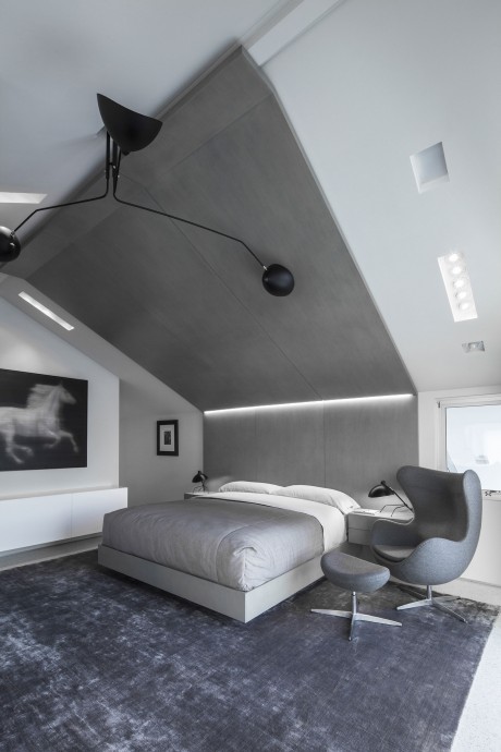 Minimalist bedroom with angular lighting fixtures, plush carpeting, and sleek furnishings.