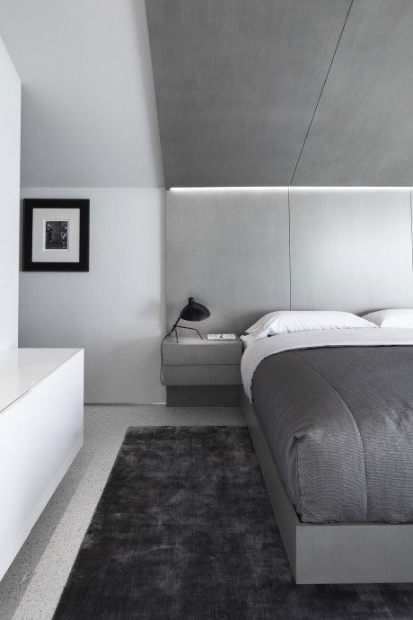 Minimalist bedroom design with gray tones, recessed lighting, and a framed artwork.
