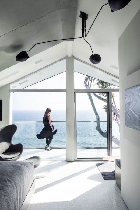 Striking modern interior with dramatic lighting, expansive windows overlooking the sea.