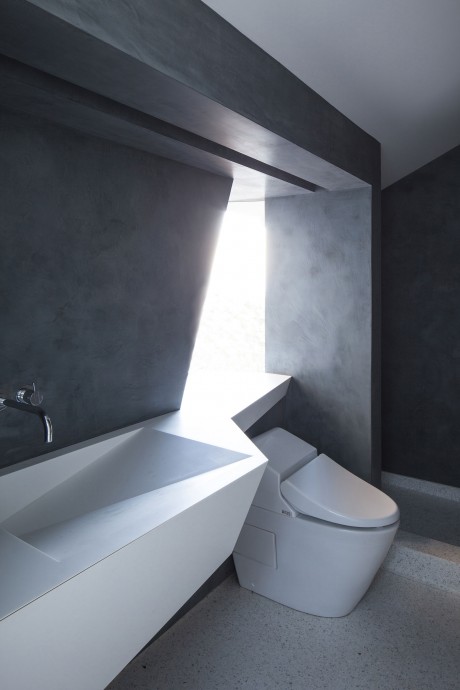 Modern minimalist bathroom with sleek concrete walls, floating vanity, and integrated toilet.