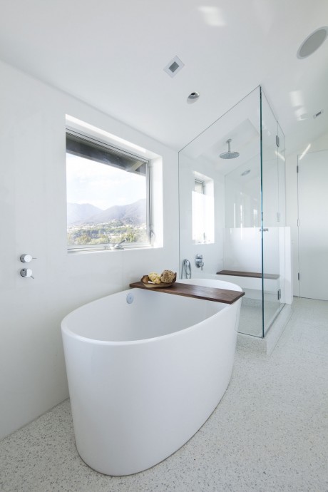 A modern, bright bathroom with a freestanding tub, glass shower, and mountain view.
