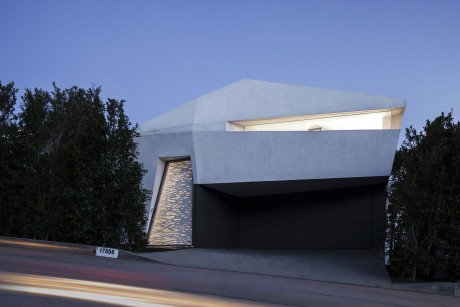 Modern gray structure with angled roofline, large windows, and landscaping.