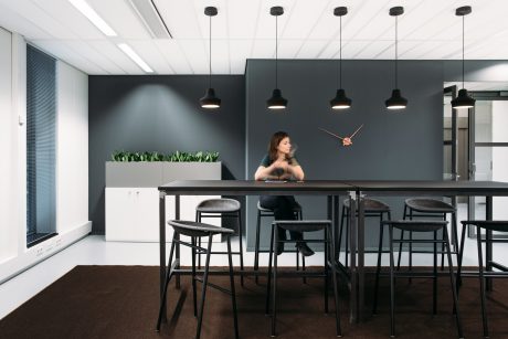 A sleek, modern office space with black walls, pendant lights, and a minimalist dining area.