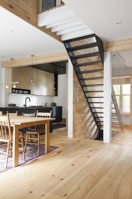 Modern, open-concept kitchen with wooden beams and metal staircase leading to upper level.