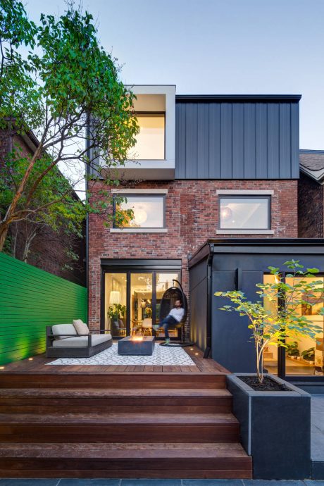 A modern home with a brick exterior, wooden deck, and landscaping accents.