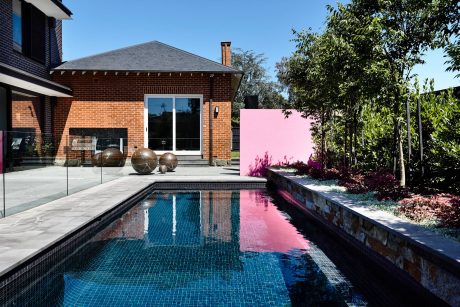 Brick exterior with sleek glass walls, pool, and modern sculptures in landscaping.